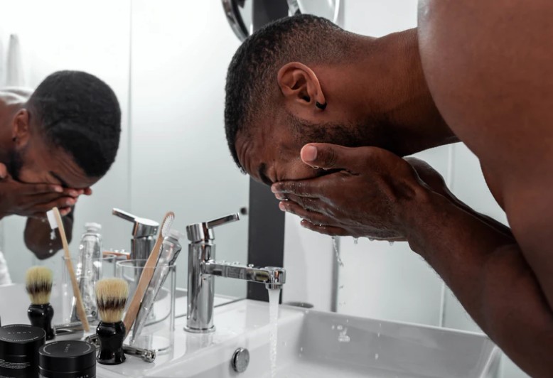 Black man washing his face at the bathroom